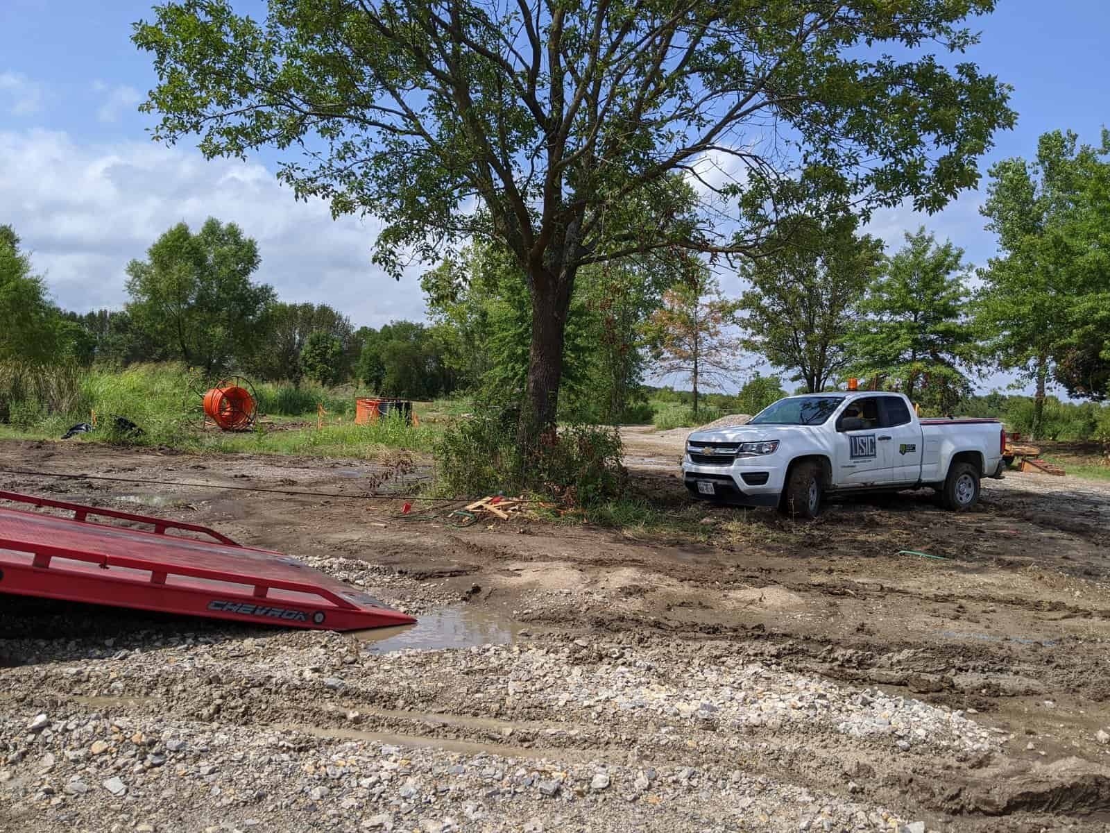 Towing truck parked near a tree on a dirt road, ready for roadside assistance.